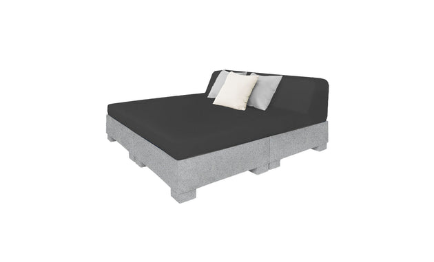 The Affinity Square Sunbed with Backrest Cushion by Ledge Lounger boasts a minimalist design with a gray mattress on a pallet-style base. It features black, white, and gray cushions against the backrest, perfect for poolside lounging or adding simple elegance to outdoor spaces.