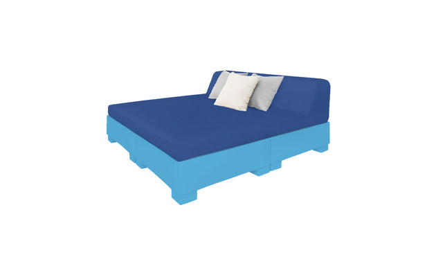 The Affinity Square Sunbed by Ledge Lounger features a blue mattress and backrest on a light blue pallet-style base, ideal for outdoor areas. Complemented by two white pillows and one gray pillow, it invites poolside relaxation, with the crisp white backdrop enhancing its serene appeal.