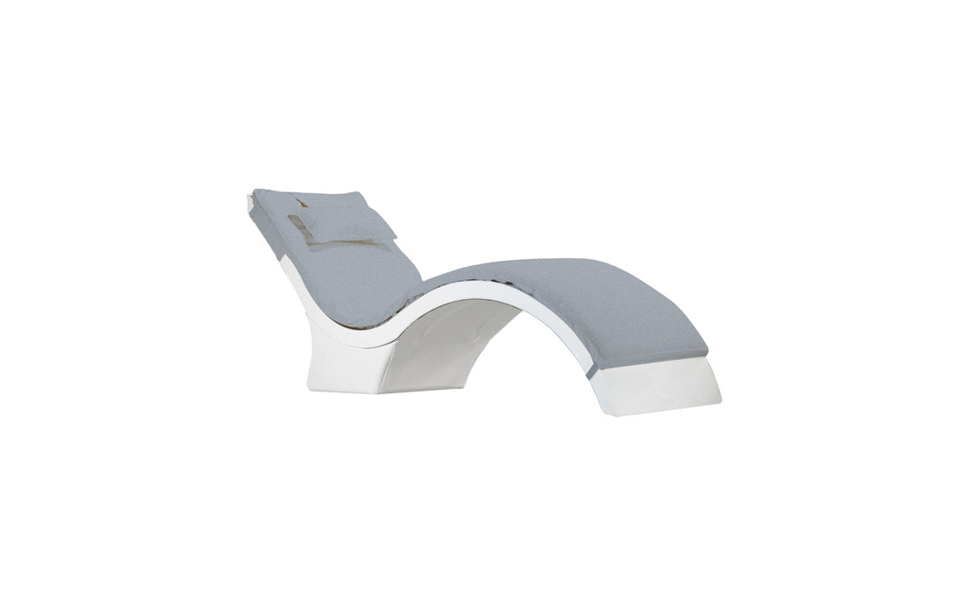The Signature Chaise Cushion by Ledge Lounger is a modern, curved lounge chair with a gray cushioned seat and backrest, plush headrest pillow, and a sleek white structure for a stylish minimalist design.