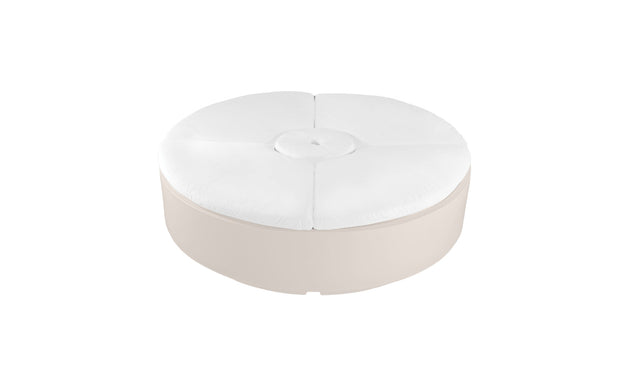 The Signature Round Sunbed by Ledge Lounger features a white cushioned top with a central tufted button detail and a beige base, making it an ideal spot for relaxation in your outdoor space.