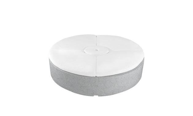 This round, grey ottoman mirrors the Signature Round Sunbed from Ledge Lounger. Ideal for outdoor areas, it features a tufted white cushion with a central button design, offering relaxation on its plain backdrop.