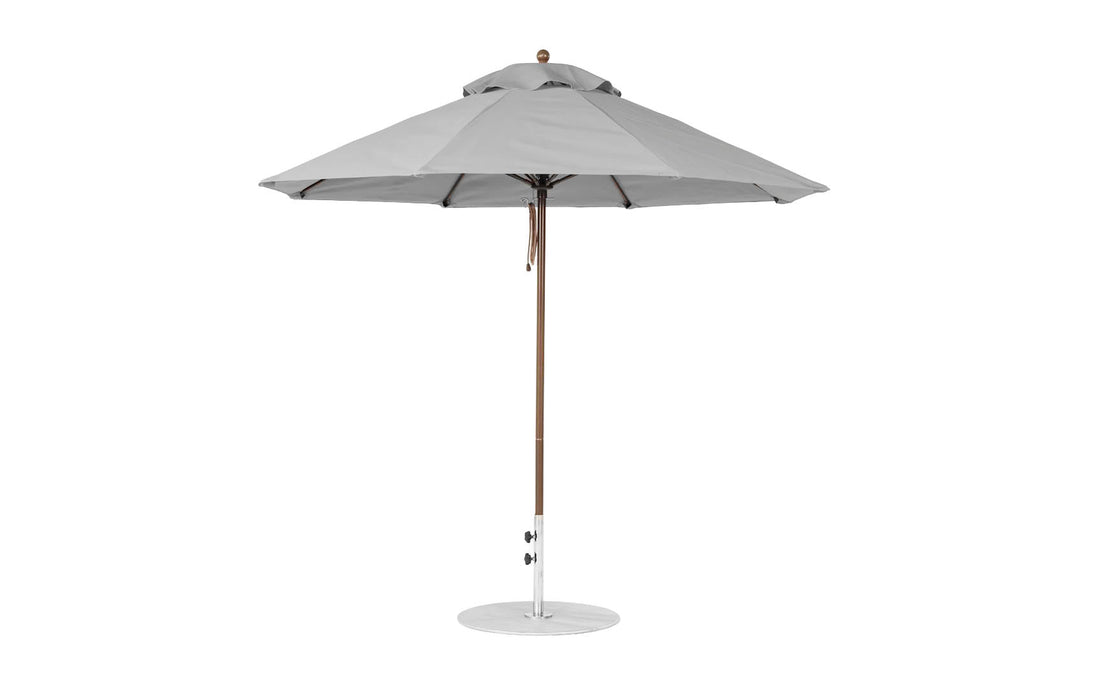 A 9 octagon Essential Fiberglass Umbrella by Ledge Lounger, featuring a large grey canopy of marine-grade fabric, fully opened with a wooden pole and circular metallic base for stability, perfect for outdoor shading.