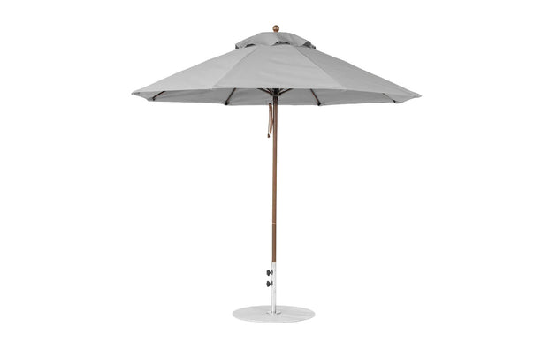 A 9 octagon Essential Fiberglass Umbrella by Ledge Lounger, featuring a large grey canopy of marine-grade fabric, fully opened with a wooden pole and circular metallic base for stability, perfect for outdoor shading.