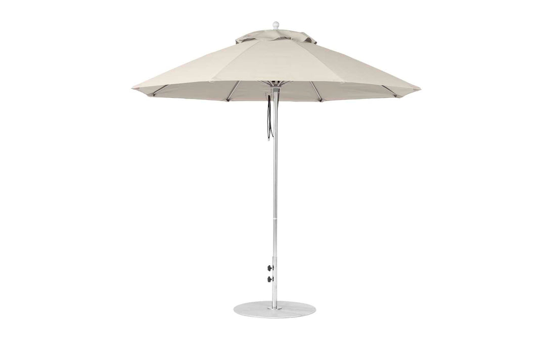 The Ledge Lounger Essential Fiberglass Umbrella features a beige canopy, sturdy aluminum pole with adjustable height, marine-grade fabrics for durability, and a round base for stability on flat surfaces.