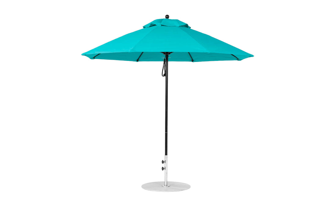 A turquoise Essential Fiberglass Umbrella by Ledge Lounger features a black pole and round metal base. The 9 octagon canopy, made from marine-grade fabric, has multiple triangular panels that converge at the top with a vent for stability.