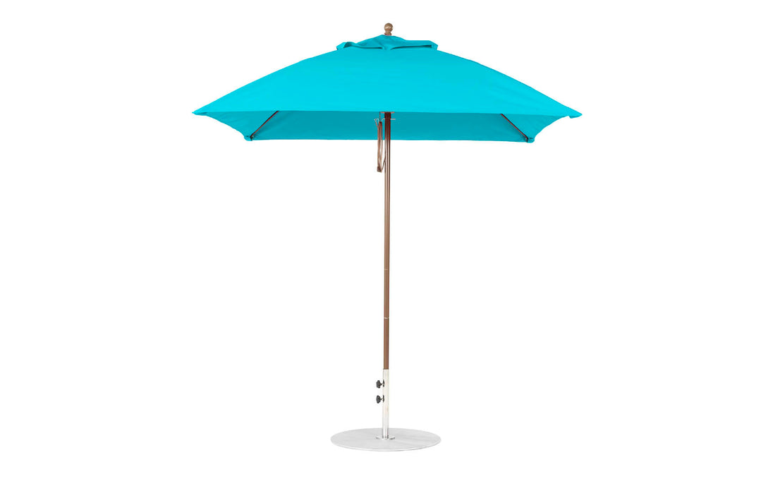 A fully open blue Ledge Lounger Essential Fiberglass Umbrella, with a 7.5 square pulley design, wooden pole, and white metal base, crafted from marine-grade fabrics featuring a classic finial on top, stands against a plain white background.