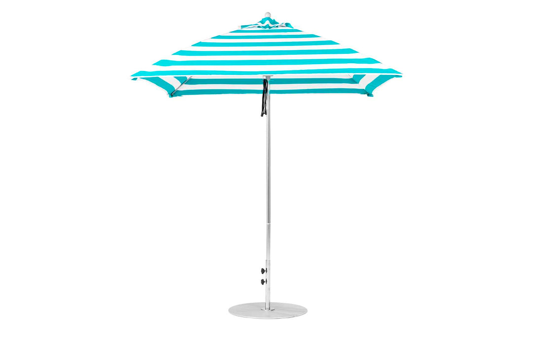 The Essential Fiberglass Umbrella by Ledge Lounger is a teal and white striped, 7.5 square design featuring a pointed top and slender pole. Crafted from marine-grade fabrics, it stands upright on a flat, round metal base for excellent durability.