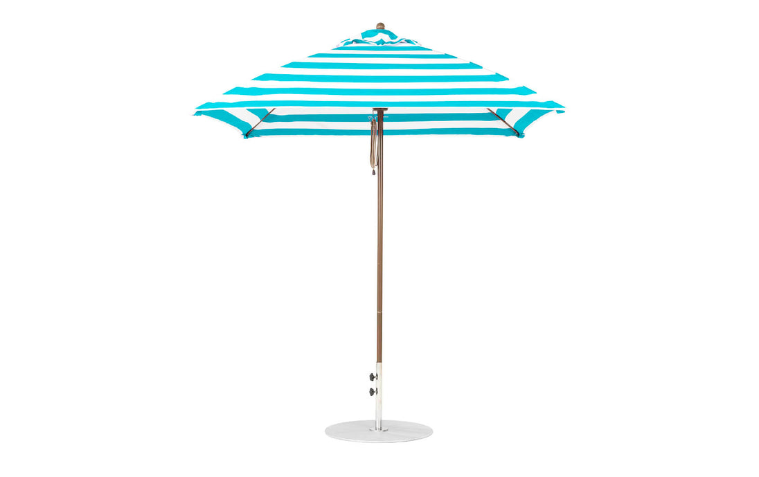 The Ledge Lounger Essential Fiberglass Umbrella - 7.5 Square Pulley features a turquoise and white striped design, a wooden pole with a round base, and is made from durable marine-grade fabrics.