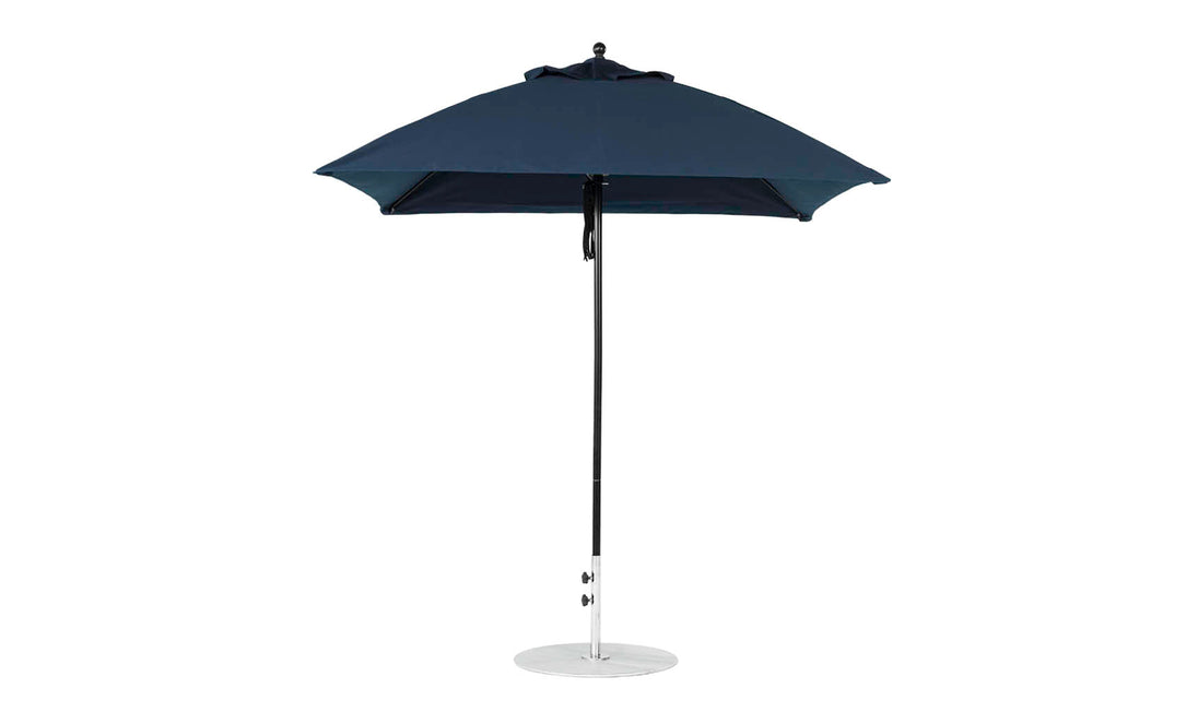 A fully opened Essential Fiberglass Umbrella - 7.5 Square Pulley, by Ledge Lounger, crafted with marine-grade fabrics in dark blue, is supported by a metal pole and round base against a plain white background.