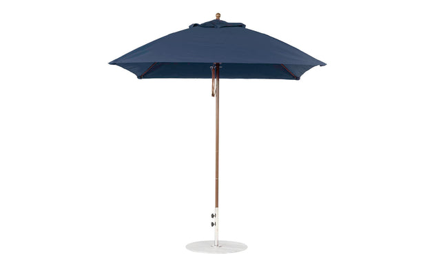 The Ledge Lounger Essential Fiberglass Umbrella features a 7.5 square canopy with marine-grade fabrics for durability, a wooden pole, and a round white base. Its stylish design offers resilience, standing fully open and upright.