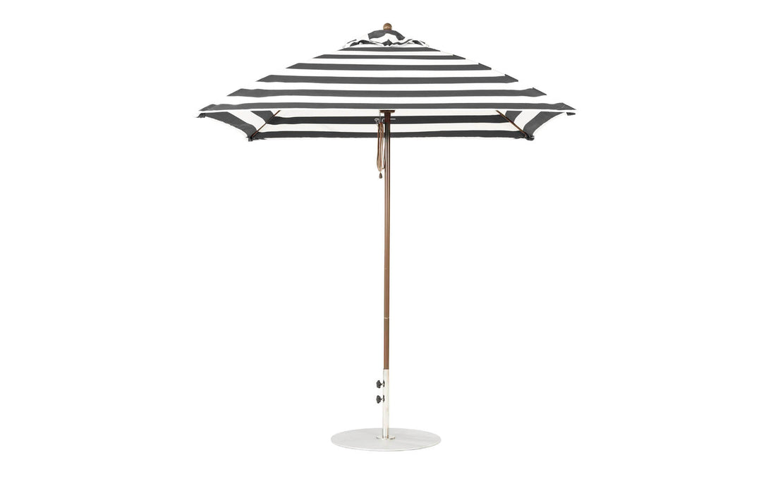 The Ledge Lounger Essential Fiberglass Umbrella in black and white stripes, with marine-grade fabric and a wooden pole, boasts a 7.5 square design with a round white base, showcasing its classic pattern when open.