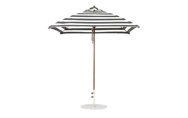 The Ledge Lounger Essential Fiberglass Umbrella in black and white stripes, with marine-grade fabric and a wooden pole, boasts a 7.5 square design with a round white base, showcasing its classic pattern when open.