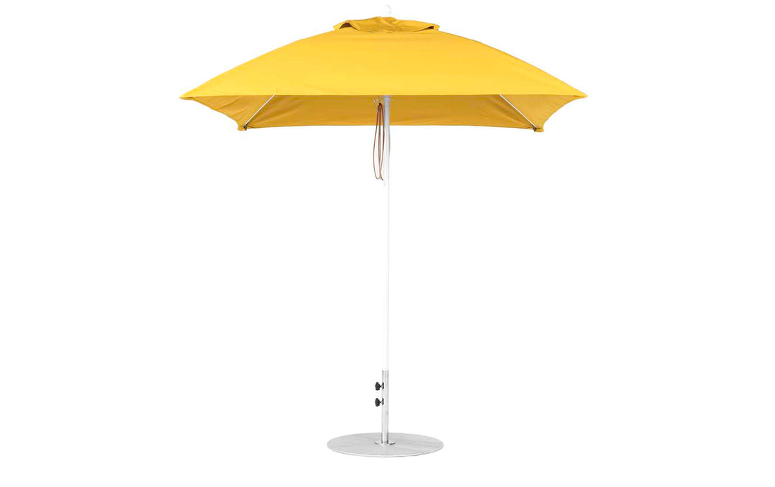 The Essential Fiberglass Umbrella by Ledge Lounger, featuring a sleek silver metal pole and round base, showcases a vibrant yellow square design with a flat top and marine-grade fabrics for lasting durability.