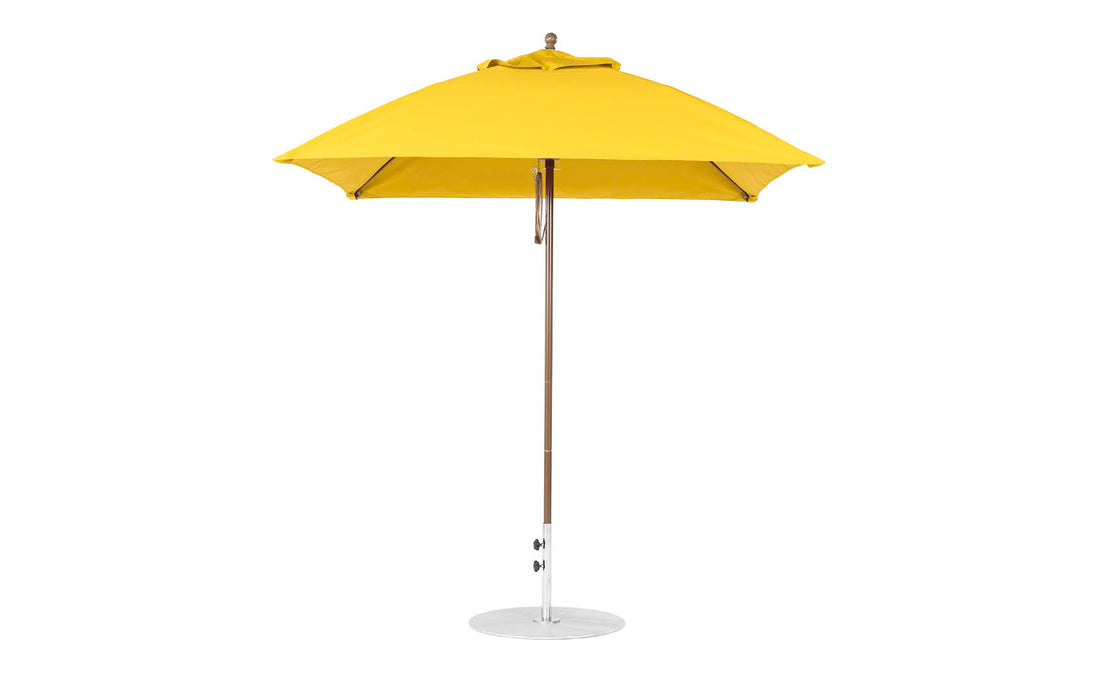 A yellow Essential Fiberglass Umbrella - 7.5 Square Pulley by Ledge Lounger features a marine-grade fabric canopy, thin silver pole, and circular base. The closed umbrella stands upright against a white background, highlighting its durable design.