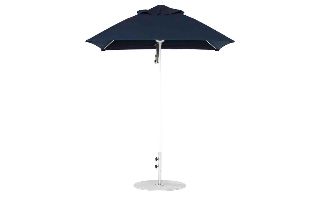 A modern Essential Fiberglass Umbrella by Ledge Lounger features a sleek conical black canopy, an aluminum center pole, and stands on a round base. It boasts durable marine-grade fabrics and a minimalist design.