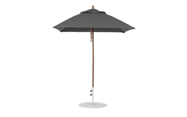 A dark gray patio umbrella by Ledge Lounger, featuring a wooden pole and round metal base, designed with marine-grade fabric. Known as the Essential Fiberglass Umbrella - 6.5 Square Pulley, it has a simple, elegant design and stands open on a flat white surface.
