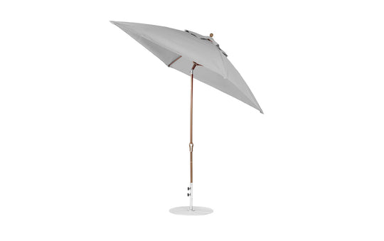 The Ledge Lounger Essential Fiberglass Umbrella, featuring a 7.5 square crank auto tilt design, has a large grey canopy made from marine-grade fabrics with a wooden pole and corrosion-resistant metal base, standing upright against a pristine white background.