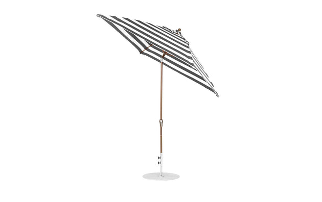 The Essential Fiberglass Umbrella by Ledge Lounger is a 7.5 square, crank auto-tilt design with a wooden pole and round base. Featuring black and white stripes, its made from marine-grade fabrics for durability and corrosion resistance, set against a white background.