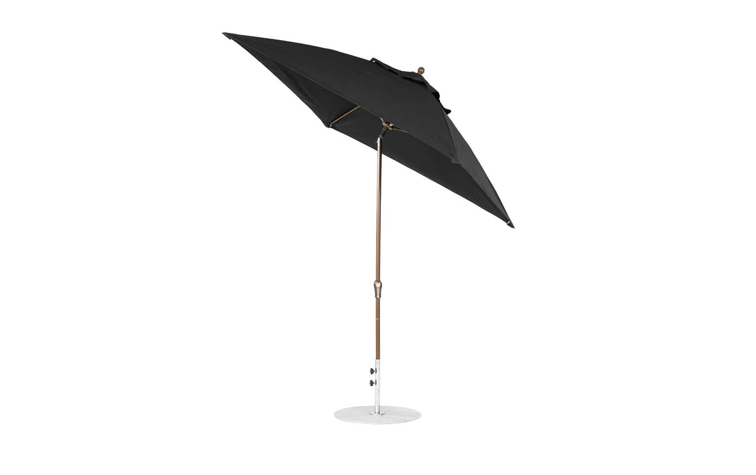 The Ledge Lounger 7.5 Square Crank Auto Tilt Essential Fiberglass Umbrella features a corrosion-resistant round white base, metal pole, and marine-grade fabrics. It is open and angled to showcase its sturdy structure against a plain white background.