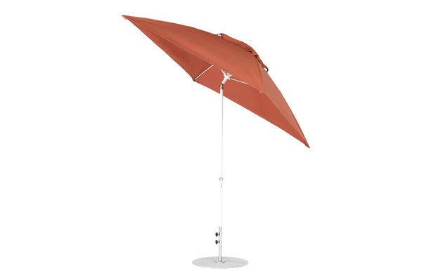 The Essential Fiberglass Umbrella by Ledge Lounger features a slim white pole and corrosion-resistant round metal base. Its rust-colored canopy is made from marine-grade fabrics, and it offers a tilt mechanism for convenience. Measures 7.5 square with a crank auto tilt against a pristine white background.