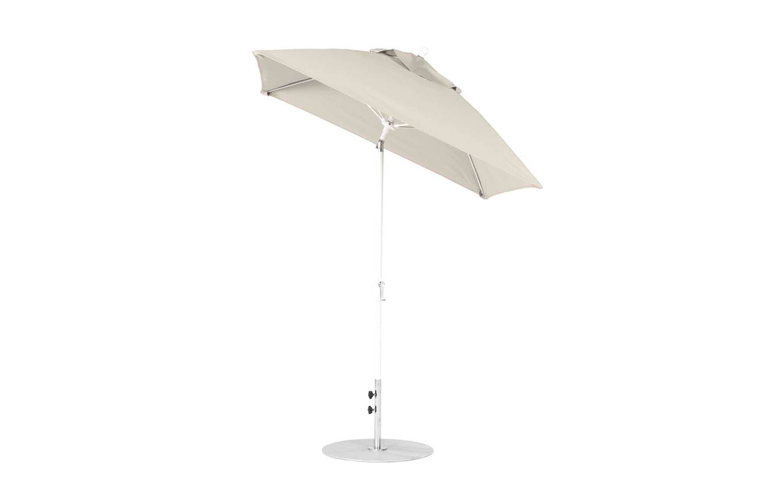 The Ledge Lounger Essential Fiberglass Umbrella features a 6.5 square canopy in beige, made from marine-grade fabrics with auto tilt and crank. It includes a modern, sleek design with a corrosion-resistant metal pole on a circular base.