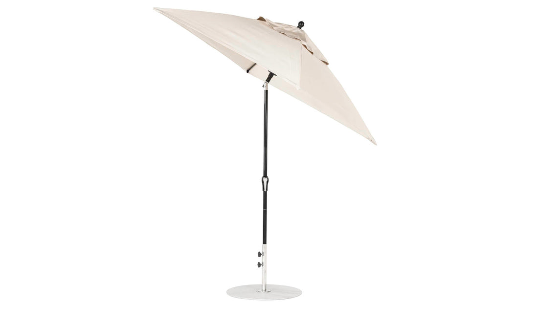 The Ledge Lounger Essential Fiberglass Umbrella features a corrosion-resistant, beige canopy made from marine-grade fabrics, elegantly positioned on a black metal pole with a round base. Perfect for patio use, this 6.5 square crank auto-tilt umbrella appears against a plain white background.
