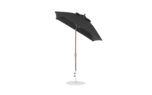 The Ledge Lounger Essential Fiberglass Umbrella - 6.5 Square Crank Auto Tilt features a black canopy with a wooden pole and round white base, made from marine-grade fabrics for durability, showcasing a modern design thats ideal for outdoor settings.