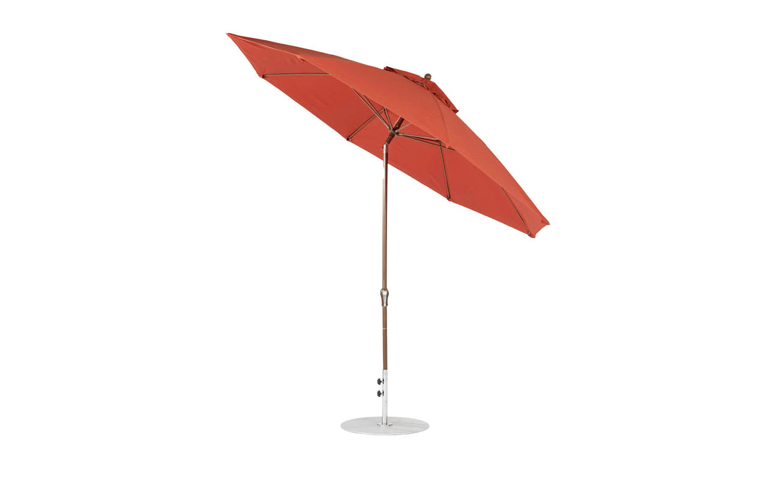 The Essential Fiberglass Umbrella by Ledge Lounger features an 11 octagonal shape, auto-tilt function, marine-grade fabrics for durability, and a decorative finial. It includes a red canopy with an aluminum center pole and white metal base.
