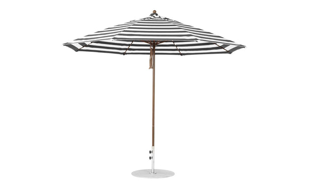 The Essential Fiberglass Umbrella by Ledge Lounger features an 11 octagon canopy in black and white stripes, supported by a wooden pole on a circular metal base. The canopy is fully open, crafted from marine-grade fabrics for enhanced durability.
