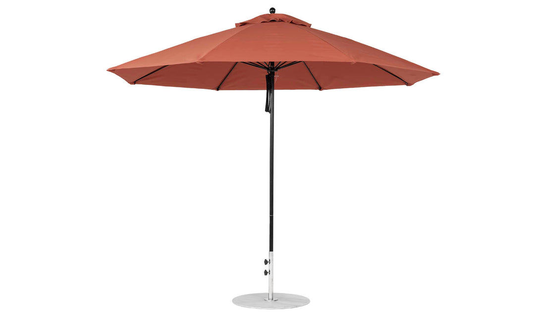 The Essential Fiberglass Umbrella - 11 Octagon Pulley by Ledge Lounger is a large, rust-colored patio umbrella with a sleek black pole and round metal base, made from marine-grade fabrics and fully open for side viewing.