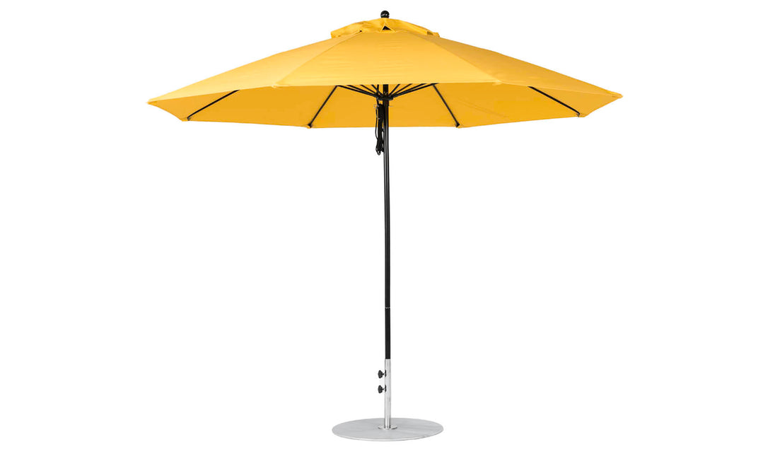 The Essential Fiberglass Umbrella - 11 Octagon Pulley by Ledge Lounger is a bright yellow, wind-resistant outdoor umbrella with a wide canopy and central metal pole, designed to stand upright on a circular base for optimal shade.