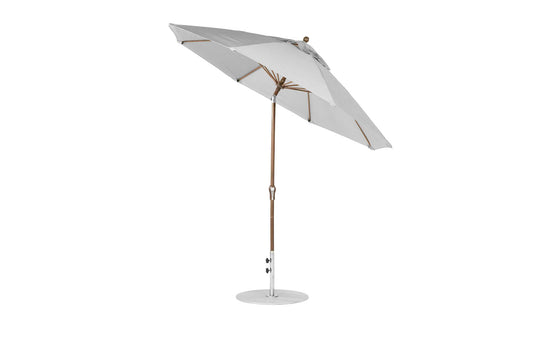 A Ledge Loungers Essential Fiberglass Umbrella features a wood pole, silver metal base, and marine-grade fabrics, open and slightly tilted against a white background. It’s an elegant, wind-resistant 9 octagon umbrella with crank auto tilt.