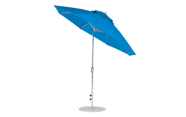 The Ledge Lounger Essential Fiberglass Umbrella features a marine-grade blue canopy with visible stitching, supported by a silver pole on a sturdy round metal base. It includes crank auto tilt functionality for adjustable shading.