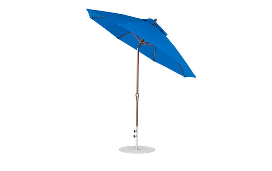 The Essential Fiberglass Umbrella - 9 Octagon Crank Auto Tilt from Ledge Lounger, in blue, boasts marine-grade fabric with a wooden pole and metal base, fully opened against a white background.