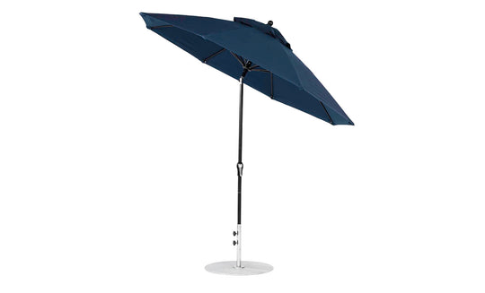 The Ledge Lounger Essential Fiberglass Umbrella - 9 Octagon Crank Auto Tilt has a dark blue marine-grade canopy and a sleek design. Its tilted canopy and sturdy black pole ensure easy adjustable shading, while the robust white base makes it ideal for any outdoor setting.