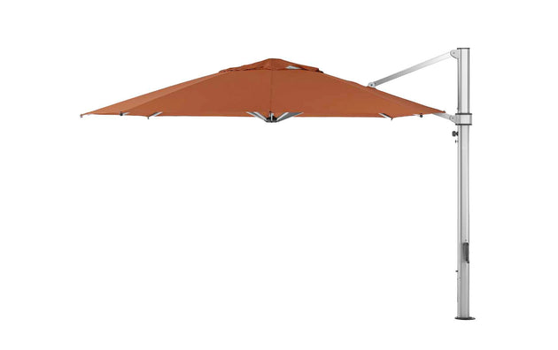 The Ledge Lounger Ultra Cantilever Umbrella - 13 Octagon features a burnt orange canopy on a silver metal pole. Its side-arm design provides unobstructed shade, and it comes with a rechargeable outdoor umbrella light, making it an ideal freestanding accent for your patio.