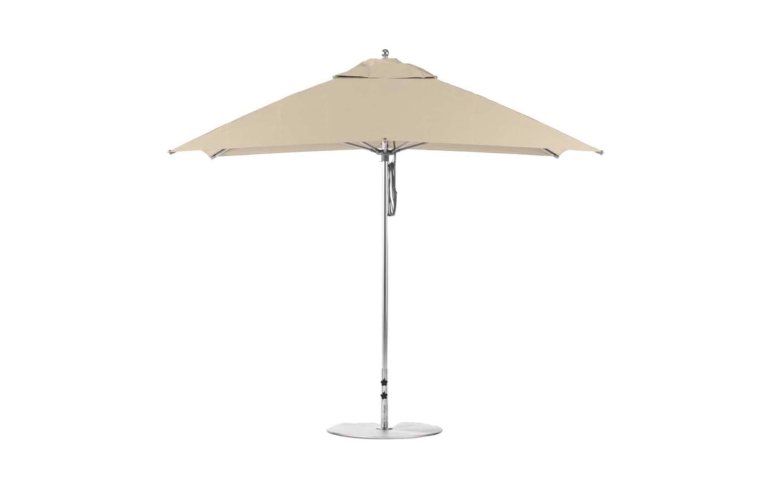 The Ledge Lounger Essential Fiberglass Umbrella - 8.5 Rectangle Pulley, viewed from the side, features a beige canopy with a silver pole and round base. Its minimalist design is crafted from wind-resistant, marine-grade fabrics, ideal for outdoor settings.