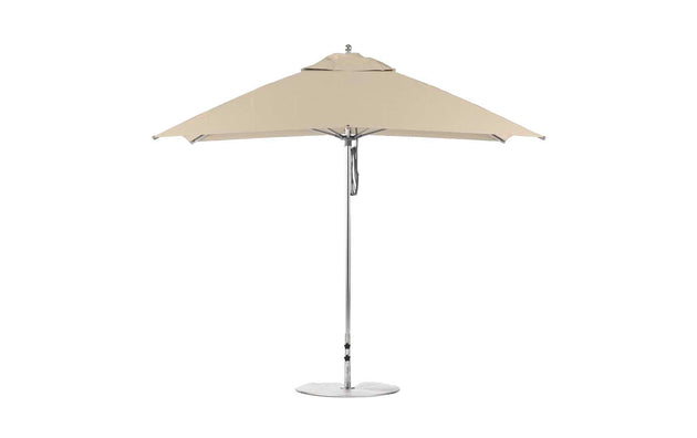 The Ledge Lounger Essential Fiberglass Umbrella - 8.5 Rectangle Pulley, viewed from the side, features a beige canopy with a silver pole and round base. Its minimalist design is crafted from wind-resistant, marine-grade fabrics, ideal for outdoor settings.