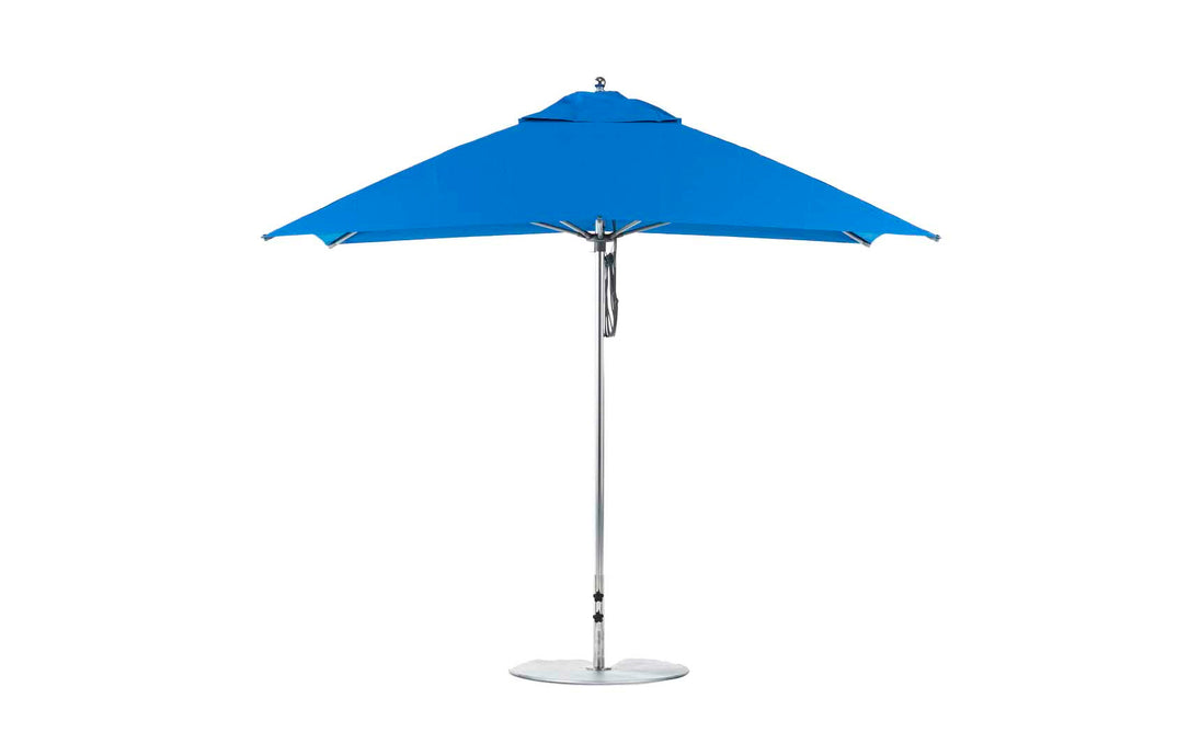 A blue Ledge Lounger Essential Fiberglass Umbrella with a silver pole and round base is open against a white background. The 8.5 rectangle pulley design features marine-grade fabrics and wind resistance for outdoor durability.