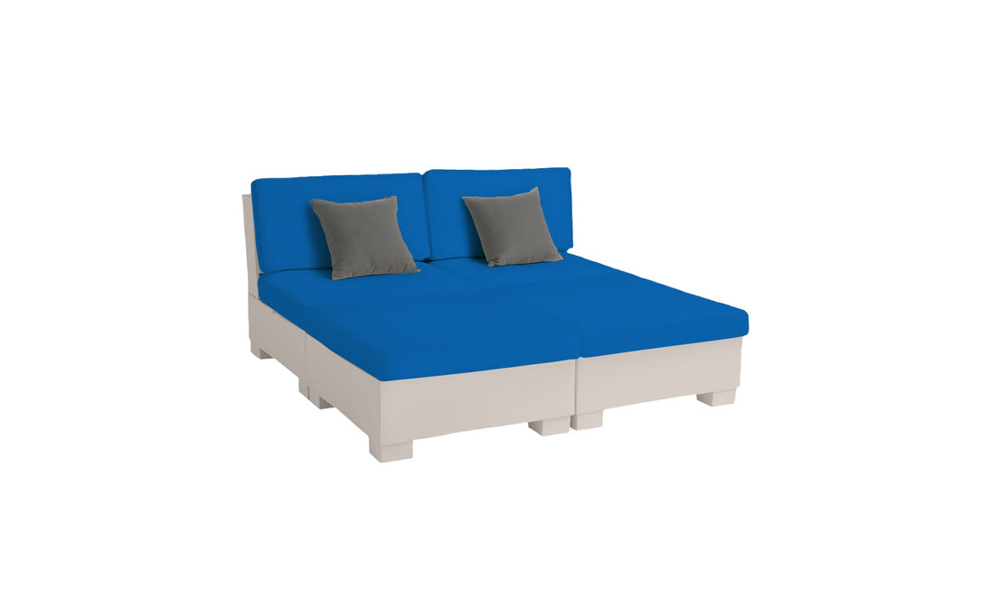 The Signature Sectional 4 Piece Sun Chair by Ledge Lounger features spacious seating with blue cushions, two gray pillows, and a light-colored base. This modular outdoor set is perfect for sun relaxation and is showcased on a plain white background.