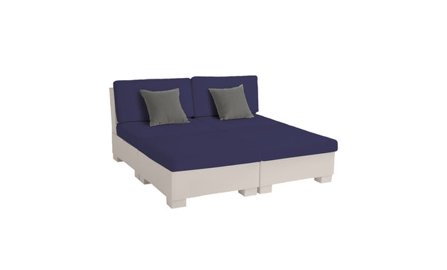 The Signature Sectional 4 Piece Sun Chair by Ledge Lounger has a cream base with navy cushions, two backrests, and two gray throw pillows. It offers spacious seating or can be arranged as a bed, seen on a white background. Perfect for relaxation.