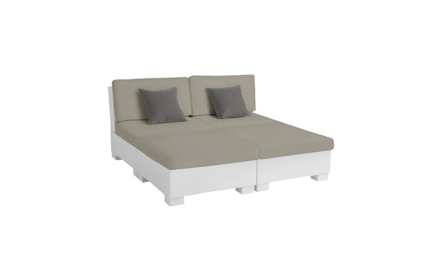 The Ledge Lounger Signature Sectional 4 Piece Sun Chair offers spacious seating and relaxation with a beige modular design and two gray throw pillows. It features a white base with square legs, set against a light background, emphasizing its contemporary style and dual functionality.