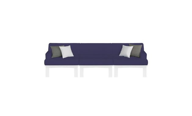 The Mainstay Sectional 3 Piece Sofa by Ledge Lounger is a long, dark blue sectional with three sections and white legs. It features two white and two dark gray throw pillows symmetrically placed against a plain white background.