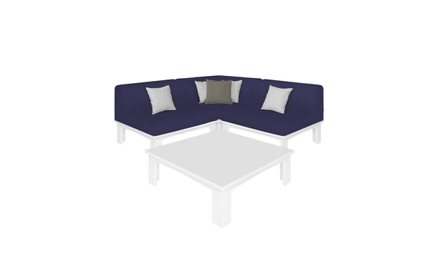 A cozy corner features the Mainstay Sectional 4 Piece Diamond in navy blue from Ledge Lounger, adorned with white and gray accent pillows, complemented by a square white coffee table, all against a plain white backdrop.