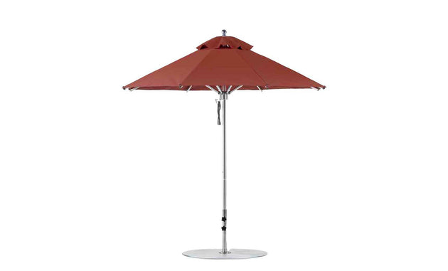 The Ledge Lounger Premier Aluminum Umbrella - 7.5 Octagon Pulley includes a wind-resistant, red patio canopy with a central metal pole on a flat, circular base. Made from marine-grade fabrics, it features a small vented top and crank mechanism for easy operation.