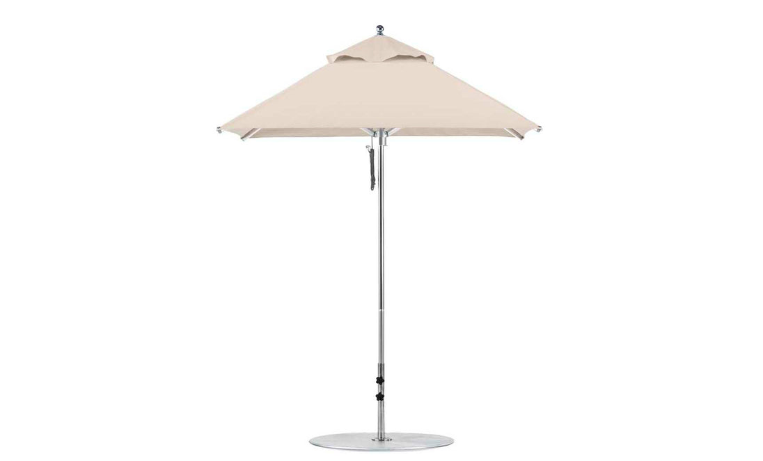 The Ledge Lounger Premier Aluminum Umbrella features a beige square canopy atop a silver pole with a circular base. Made from marine-grade fabrics, this umbrella includes a pulley system for easy adjustments and offers wind resistance for stability.