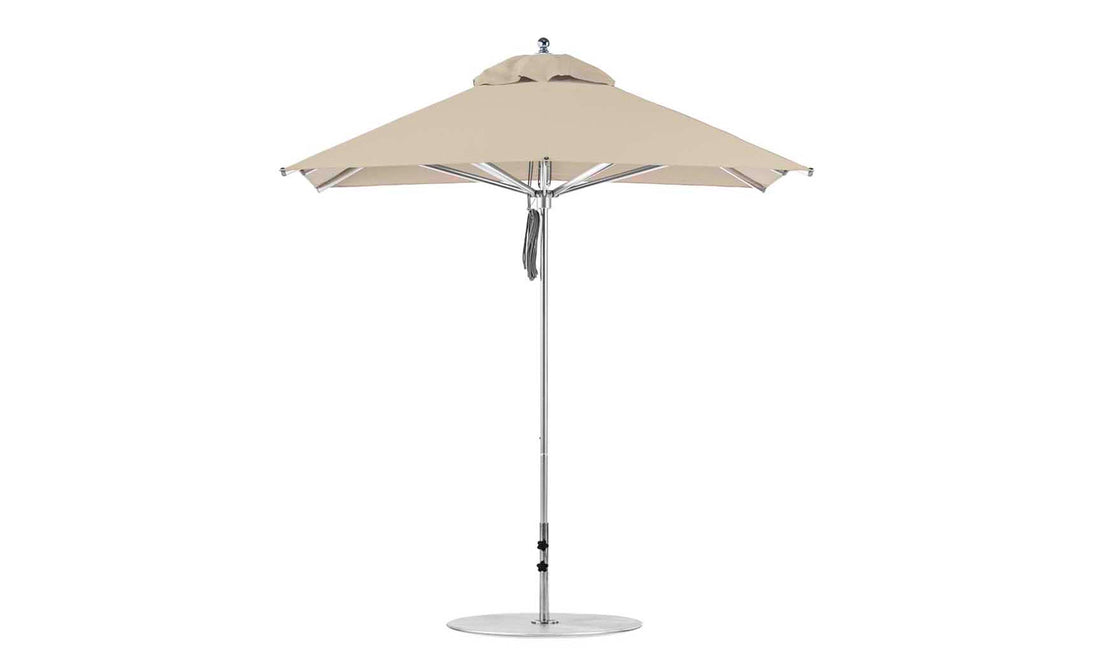 The Ledge Lounger Premier Aluminum Umbrella - 7.5 Square Pulley features a sturdy silver pole with a beige top and round base. Its vented design allows airflow, and its marine-grade fabrics enhance durability, making it wind-resistant and perfect for outdoor use.