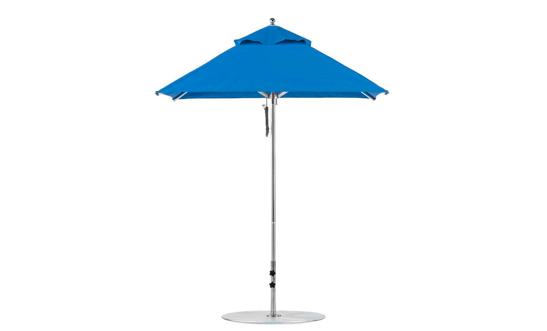 The Ledge Lounger Premier Aluminum Umbrella features a wind-resistant design with marine-grade fabrics, an aluminum pole, and a sturdy round base. The 6.5 square pulley model is fully opened for beach use.