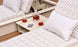 Two patterned lounge chairs with triangle designs, each topped with a white pillow. The Echo Side Table by Ledge Lounger holds a decanter, two glasses filled with amber liquid, and a deck of cards on a wooden deck.
