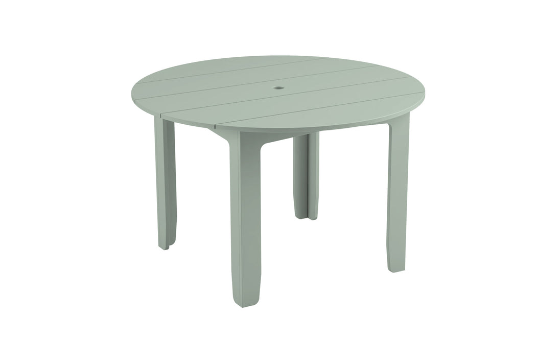 The Mainstay Round Dining Table by Ledge Lounger is light green and round, ideal for outdoor dining. It features four angled legs, a slatted surface, and a built-in umbrella sleeve at its center.